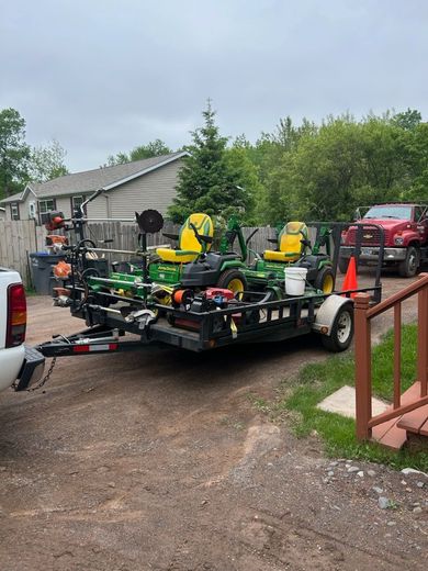 A trailer with a lawn mower on it is being towed by a truck.