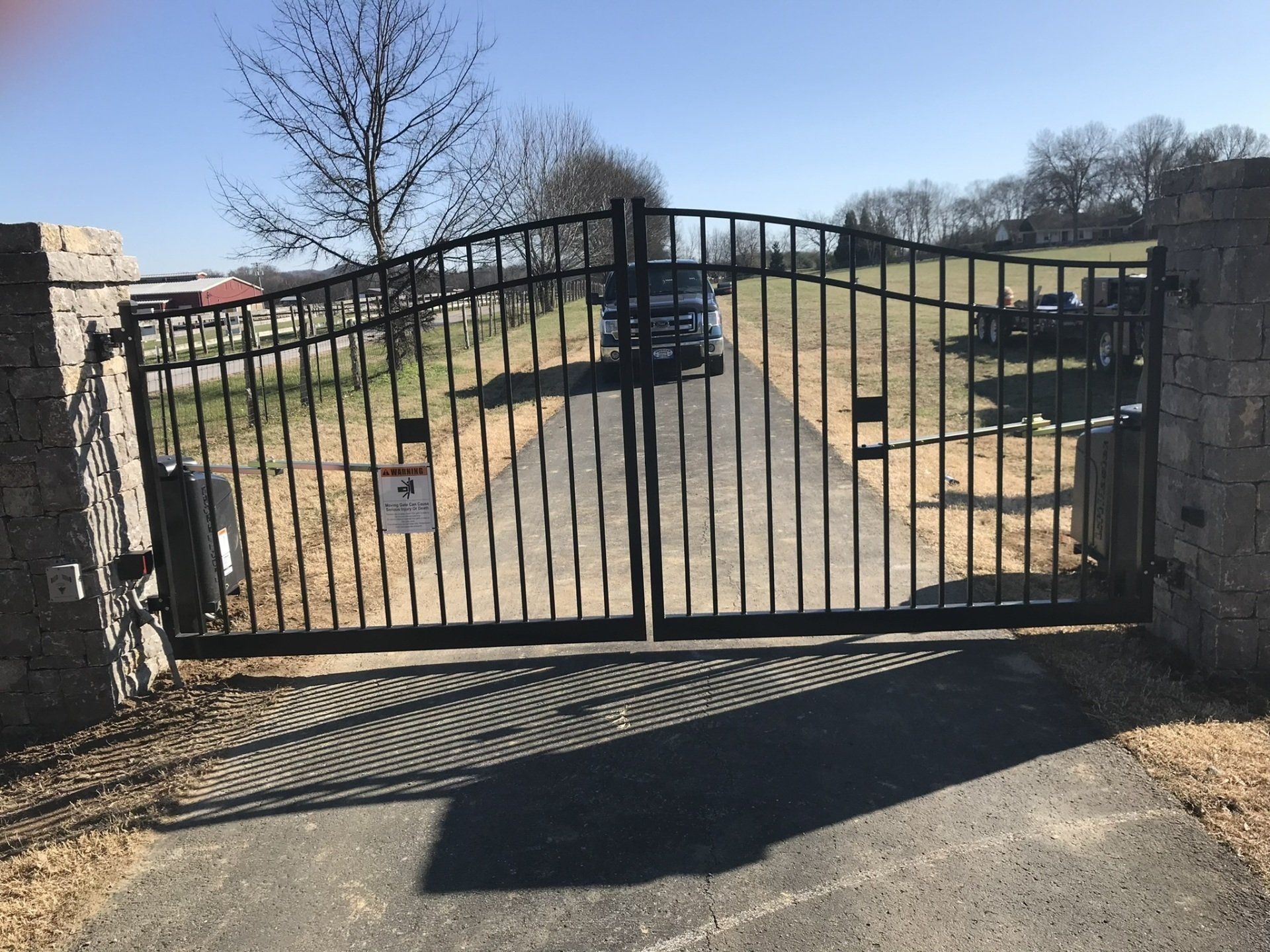 a black wrought iron gate is open to a driveway .