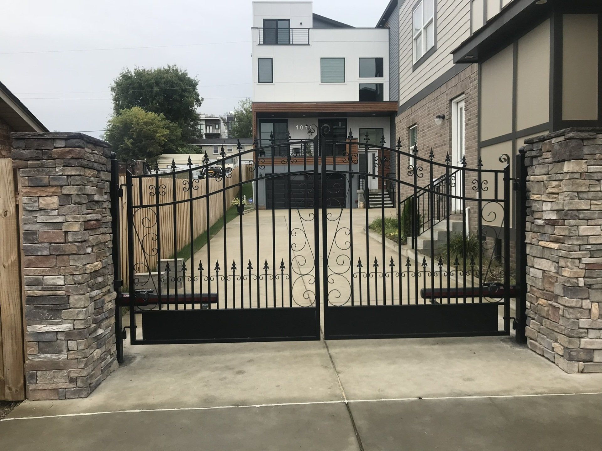 a black gate is open to a driveway in front of a house .