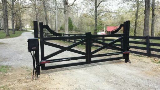 a black gate is sitting on the side of a dirt road .