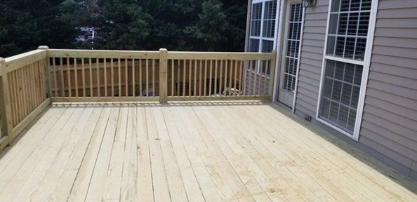 a large wooden deck with a wooden railing in front of a house .