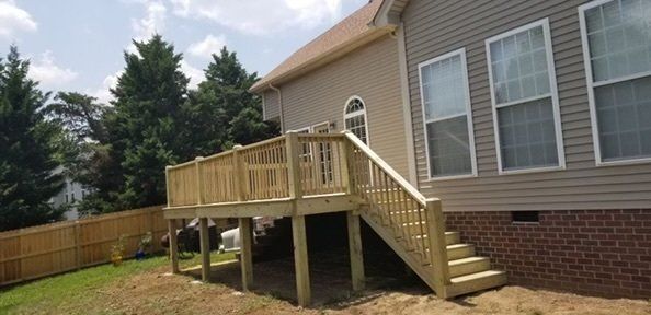 a house with a wooden deck and stairs in front of it .