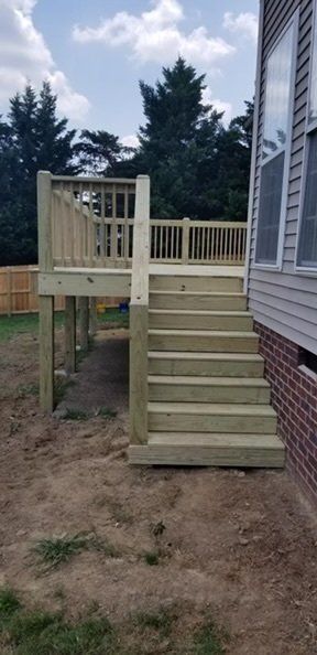 a wooden deck with stairs leading up to it next to a brick house .