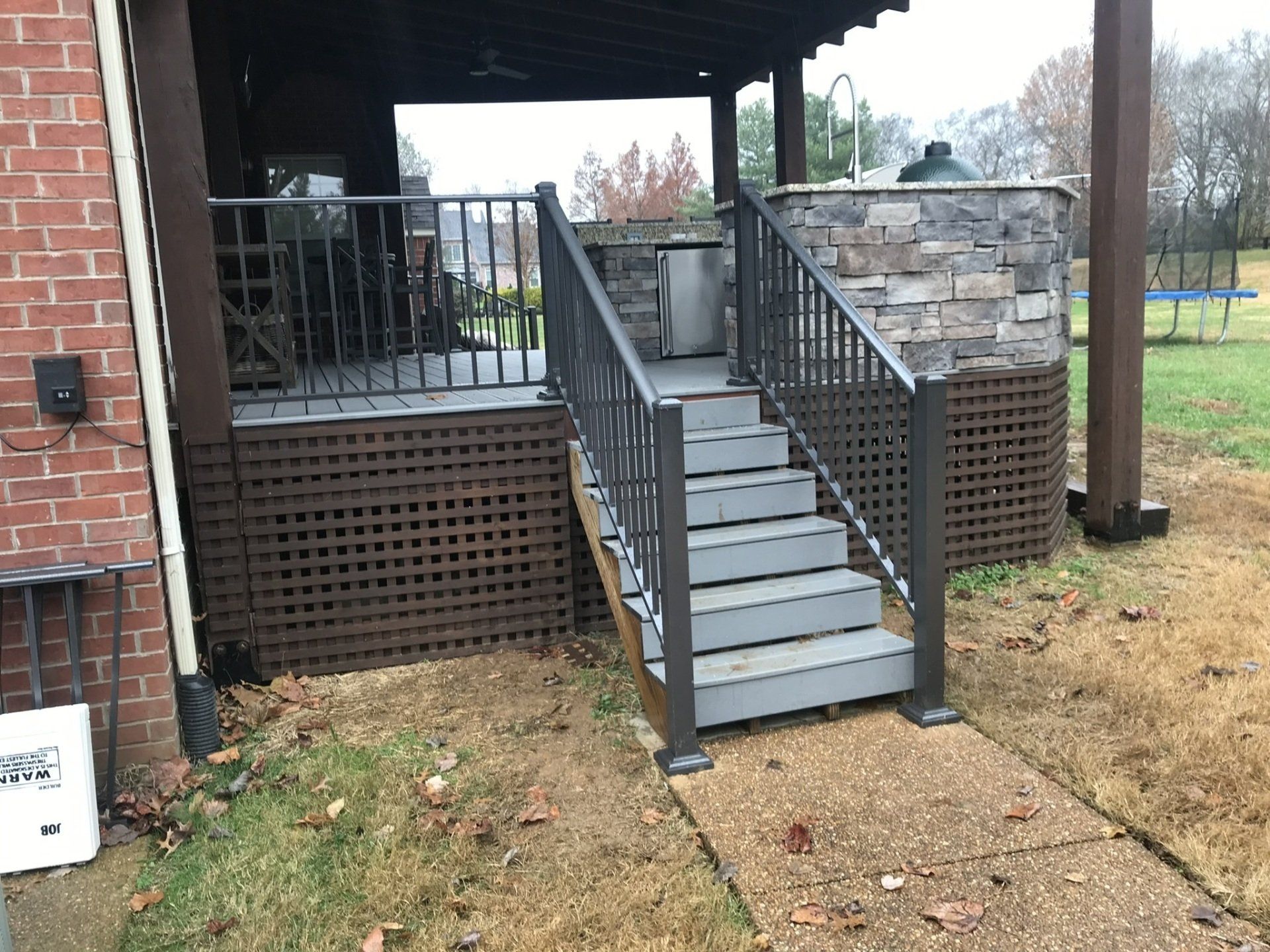 a deck with stairs leading up to it and a brick wall behind it .
