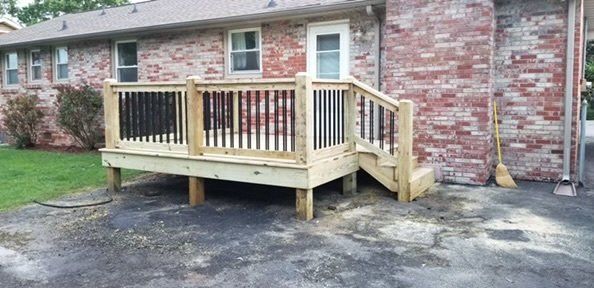 a wooden deck is sitting in front of a brick house .