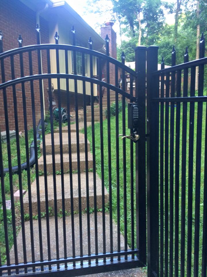 a black wrought iron gate leading to a brick house