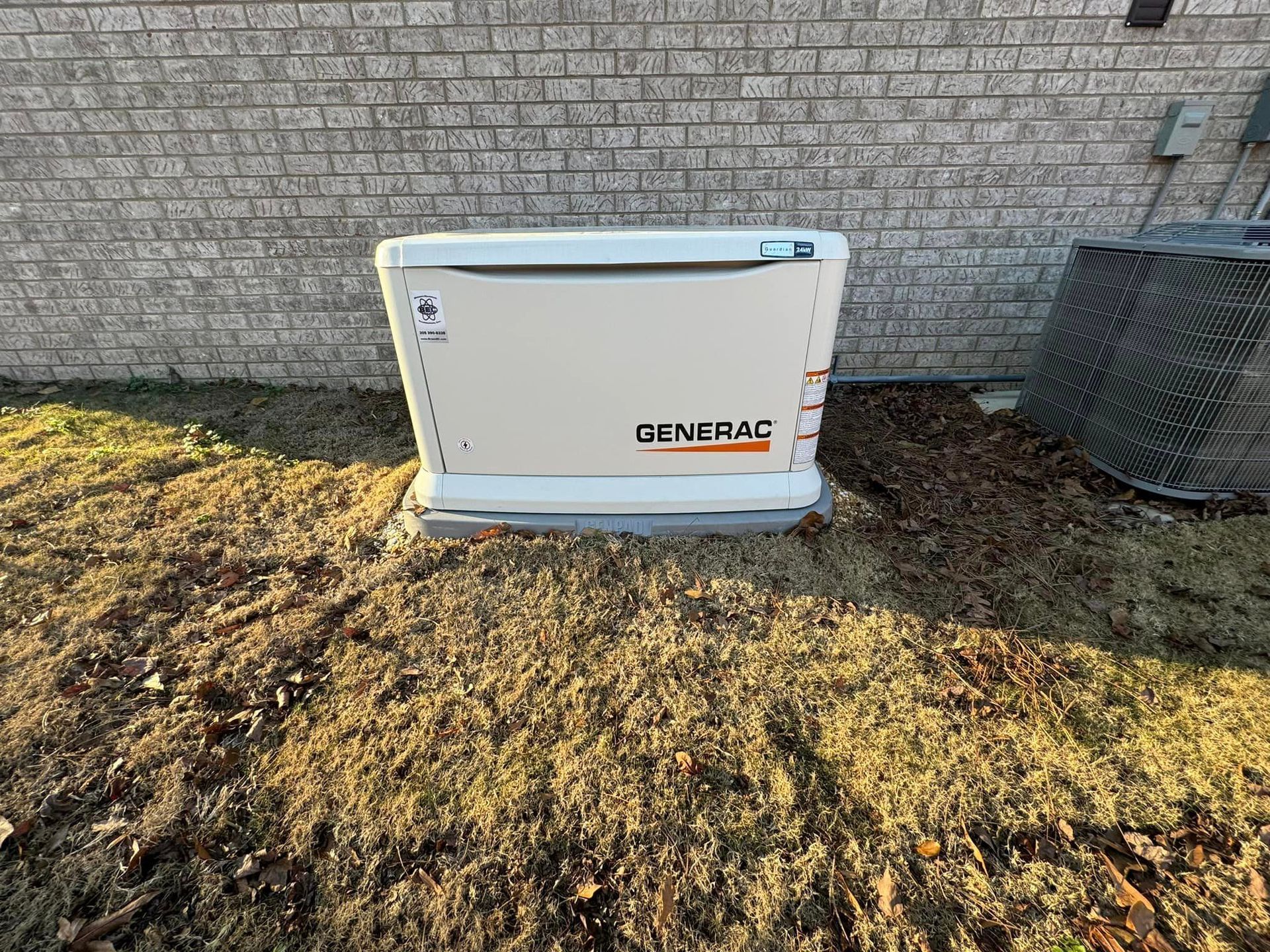 A generator is sitting in the grass in front of a brick building.