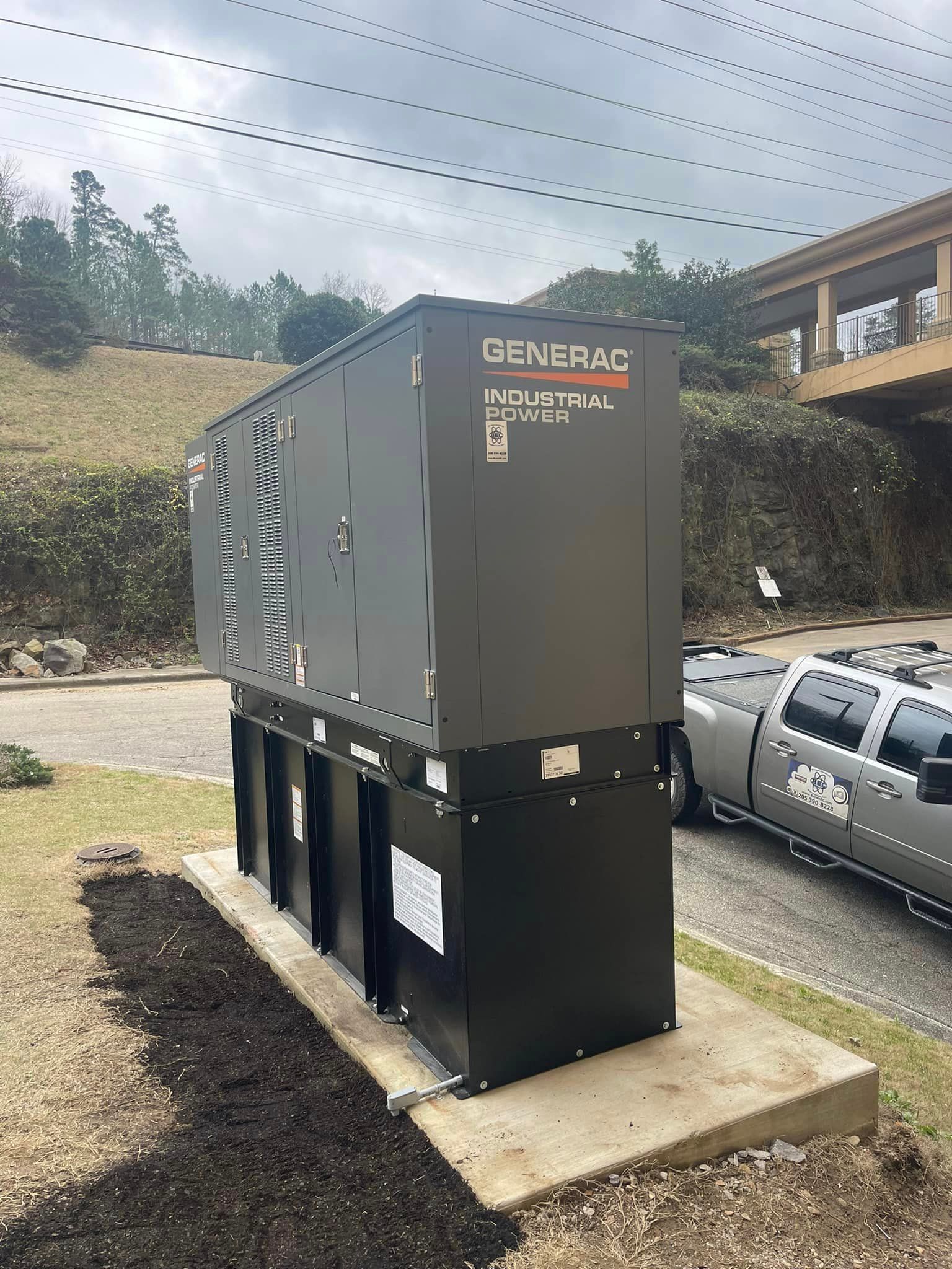 A generator is sitting on top of a concrete platform in front of a building.