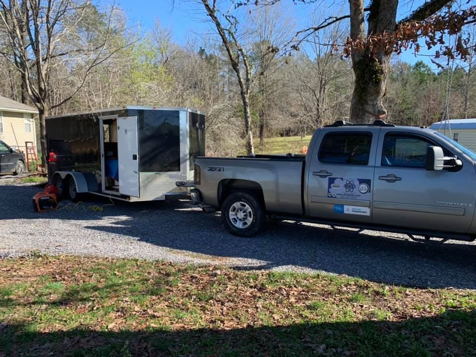 A truck with a trailer attached to it is parked in a driveway.