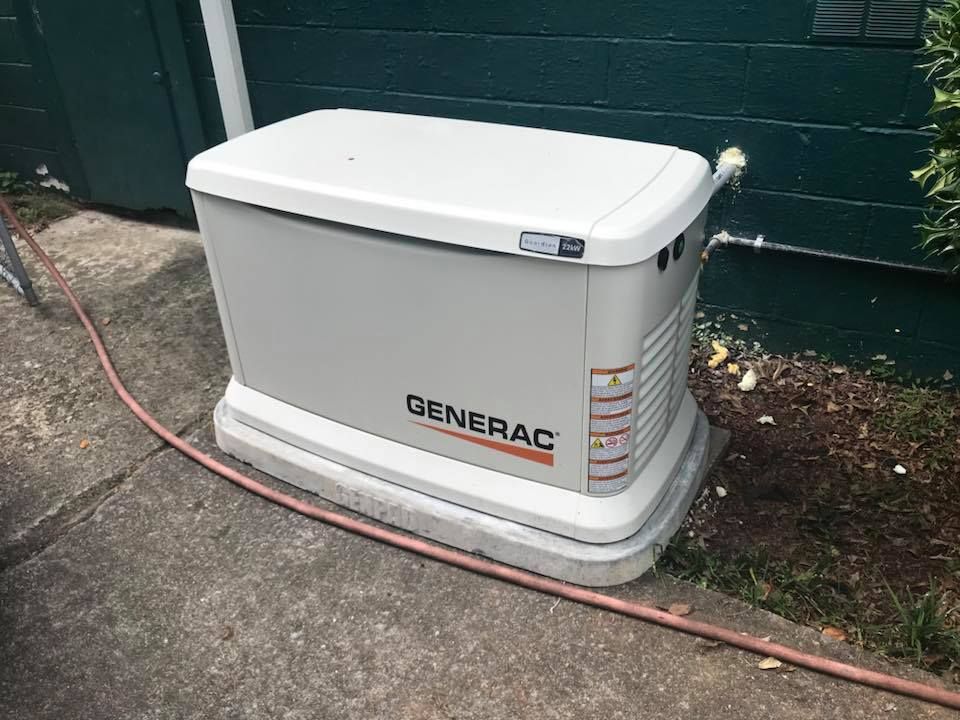 A generator is sitting on the sidewalk next to a hose.