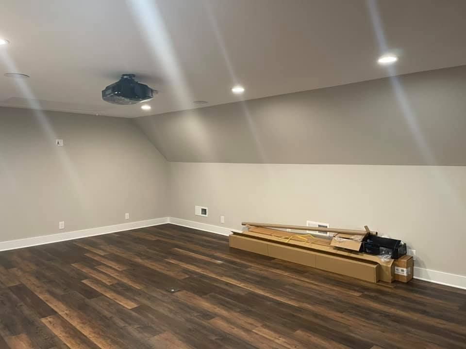 An empty room with wooden floors and a projector on the ceiling.