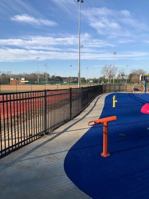 A fence surrounds a playground with a fence in the background