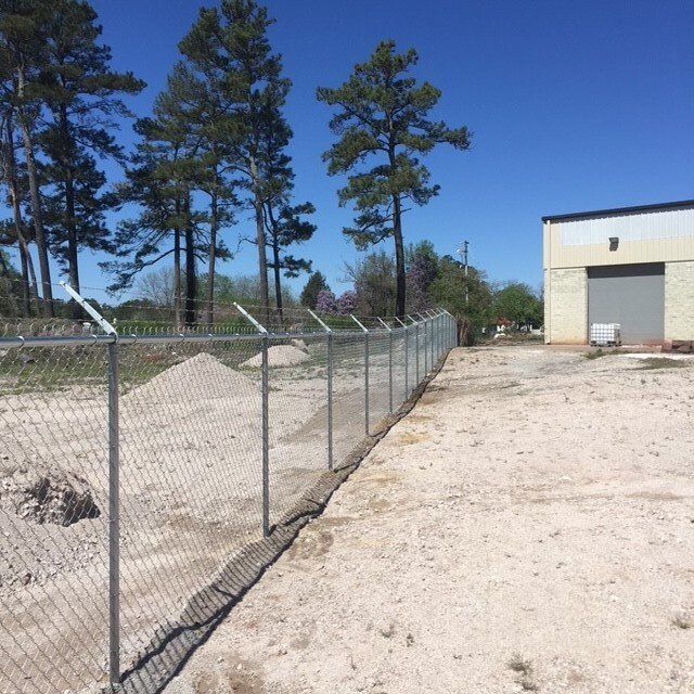 A chain link fence along the side of a dirt road