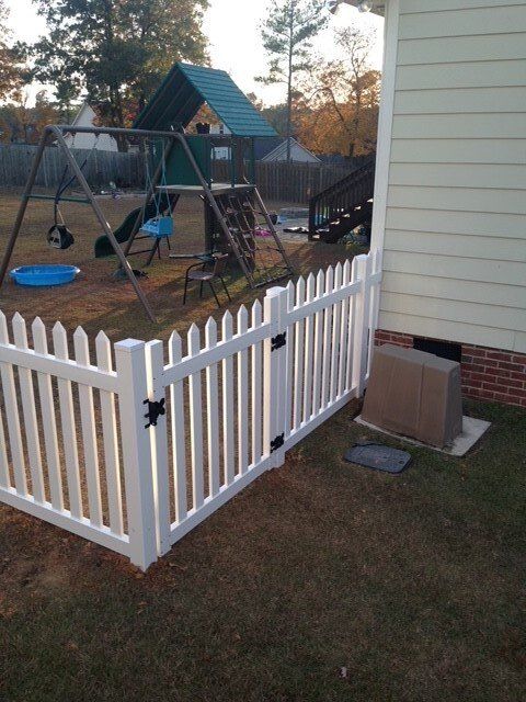 A white picket fence surrounds a playground in a backyard