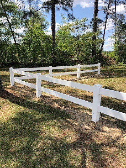 A white fence is in the middle of a grassy field.