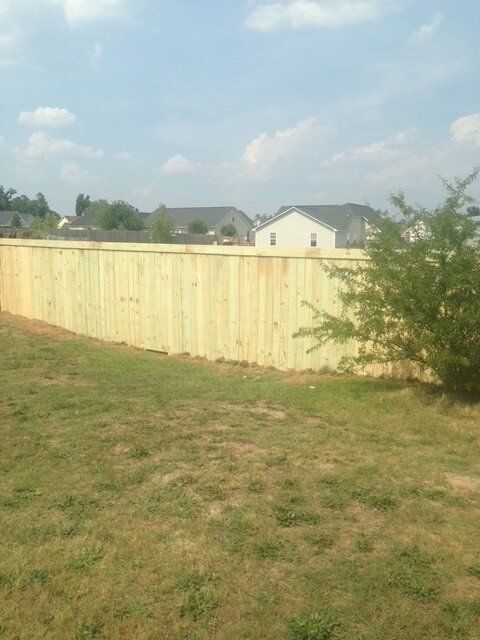 A wooden fence is in the middle of a grassy field.