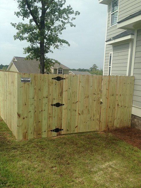 A wooden fence with a gate in the backyard of a house.