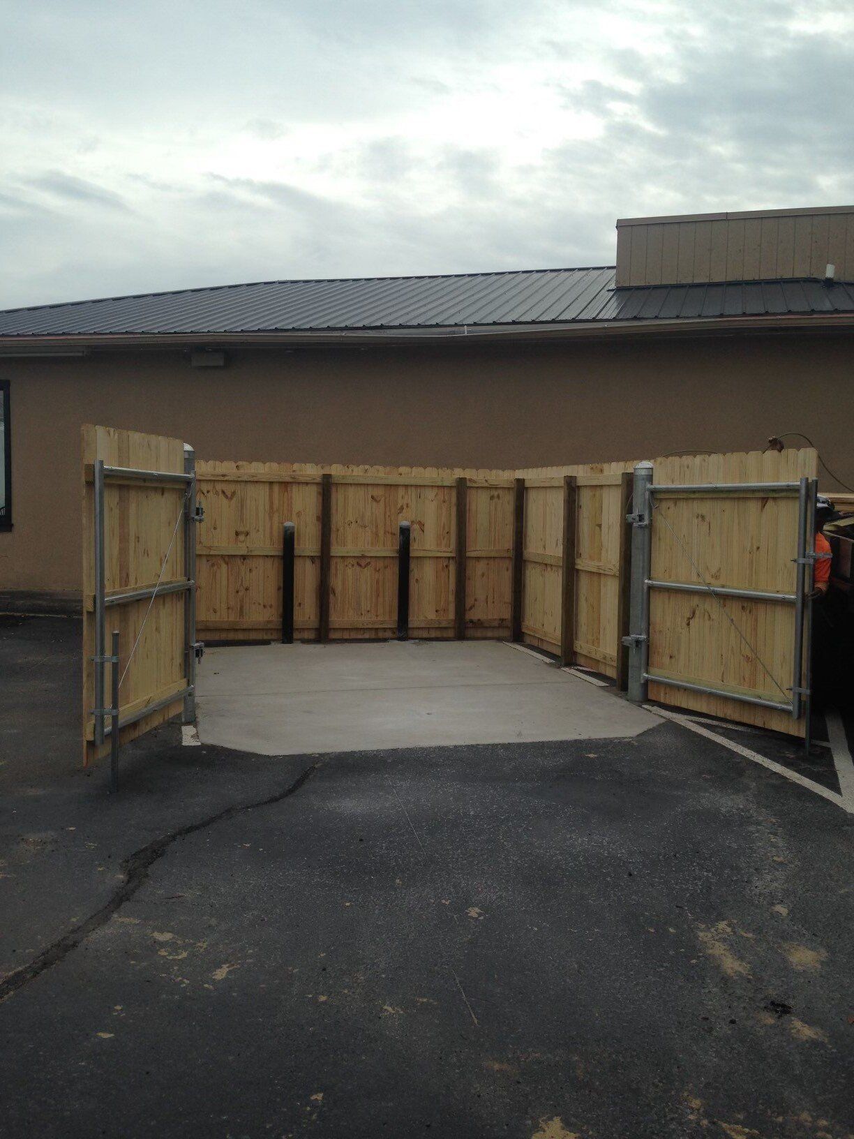 A wooden fence surrounds a parking lot in front of a building