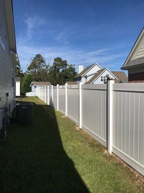 There is a white fence in the backyard of a house.