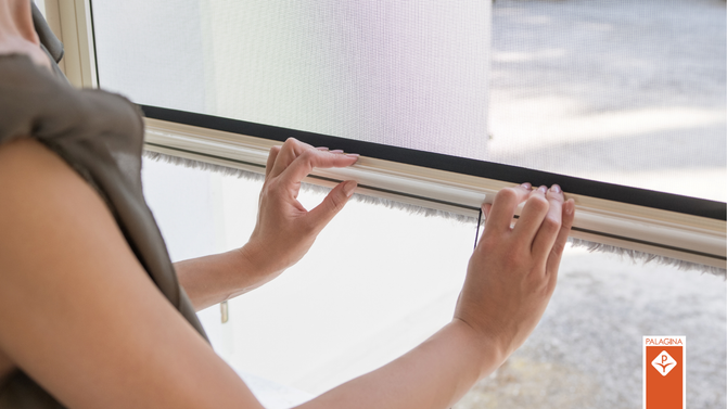 Una persona regola una zanzariera a scomparsa tenendo la maniglia del telaio.