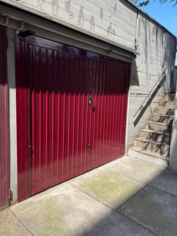 Un edificio ornato, color salmone, con finestre ad arco e un grande portone di legno, con persone che camminano per strada al di sotto.