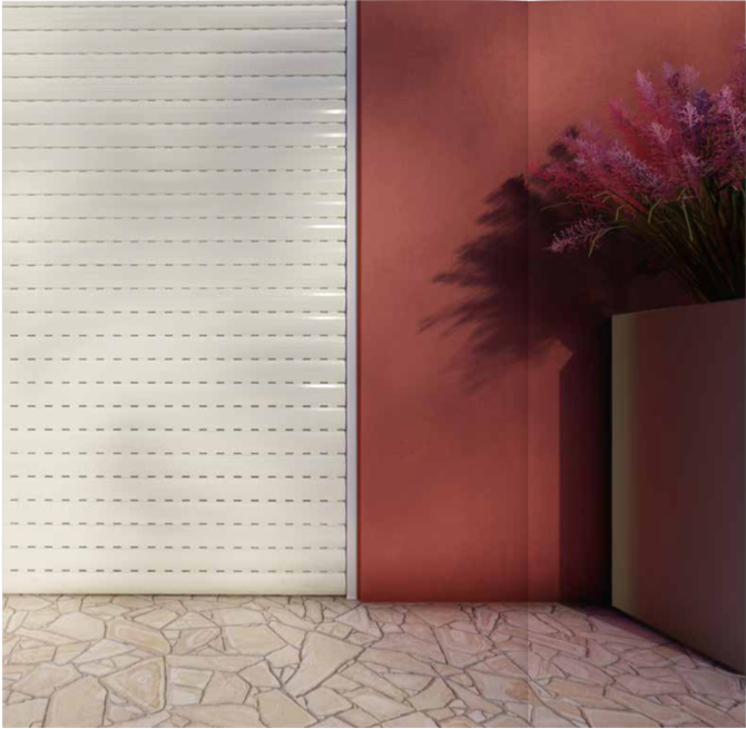 Una serranda avvolgibile bianca è posizionata accanto a un muro color marrone rossastro con una pianta ornamentale in un vaso, su un patio piastrellato in pietra.