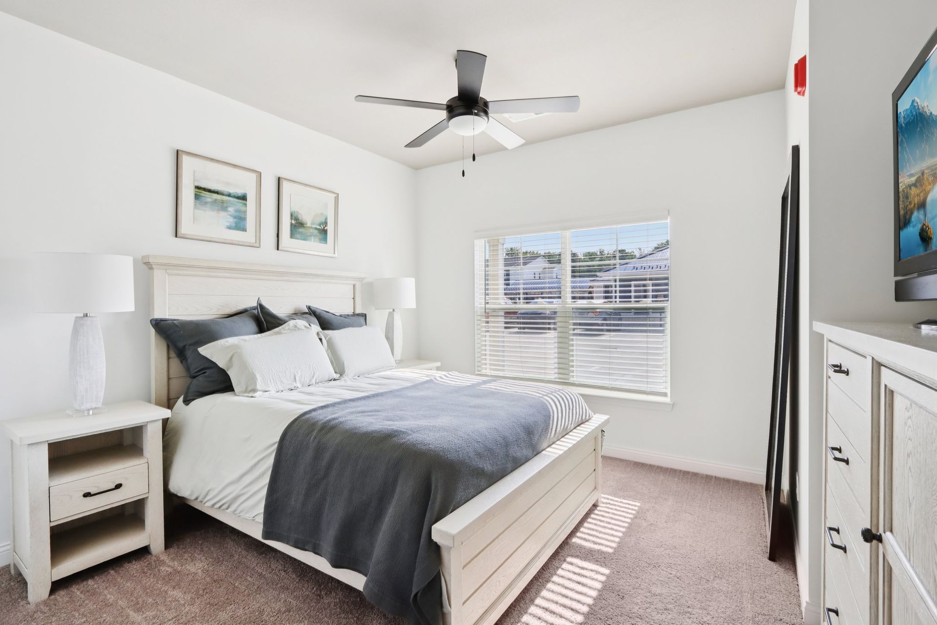 A bedroom with a bed , nightstands , lamps and a window.
