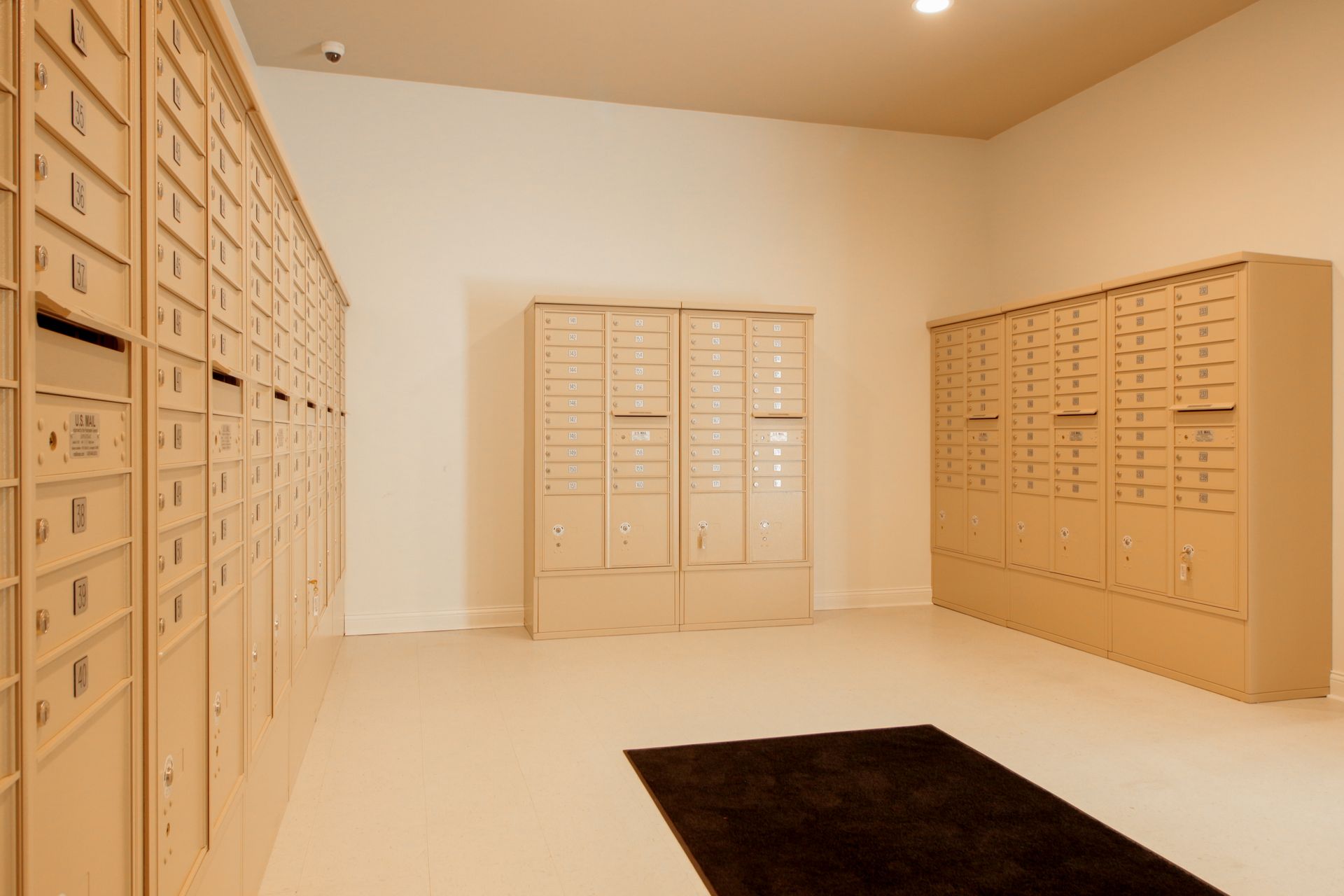 A room filled with lots of mailboxes and a black rug.