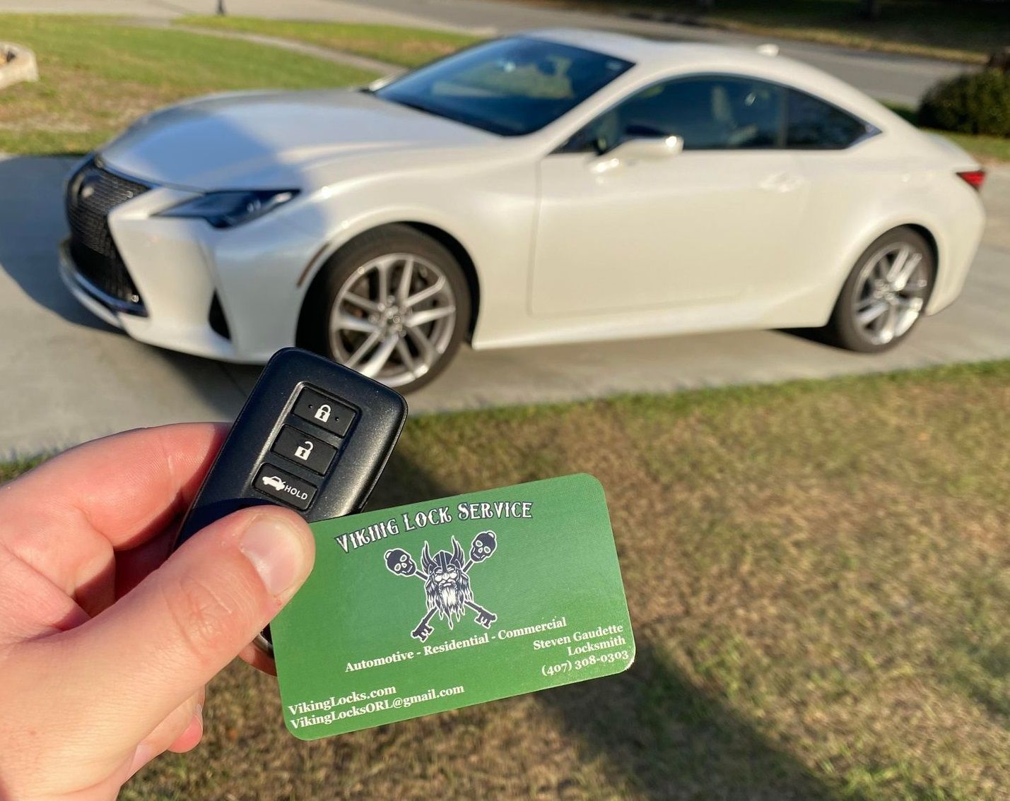 A person is holding a car key in front of a white car