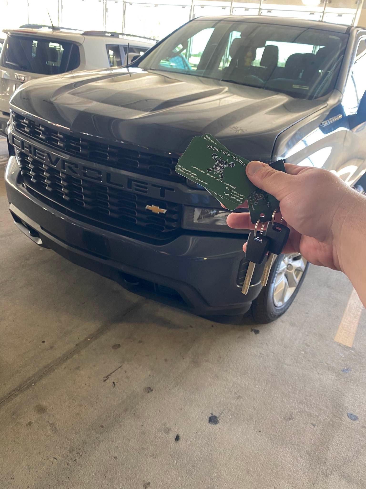 A person is holding a credit card in front of a car.