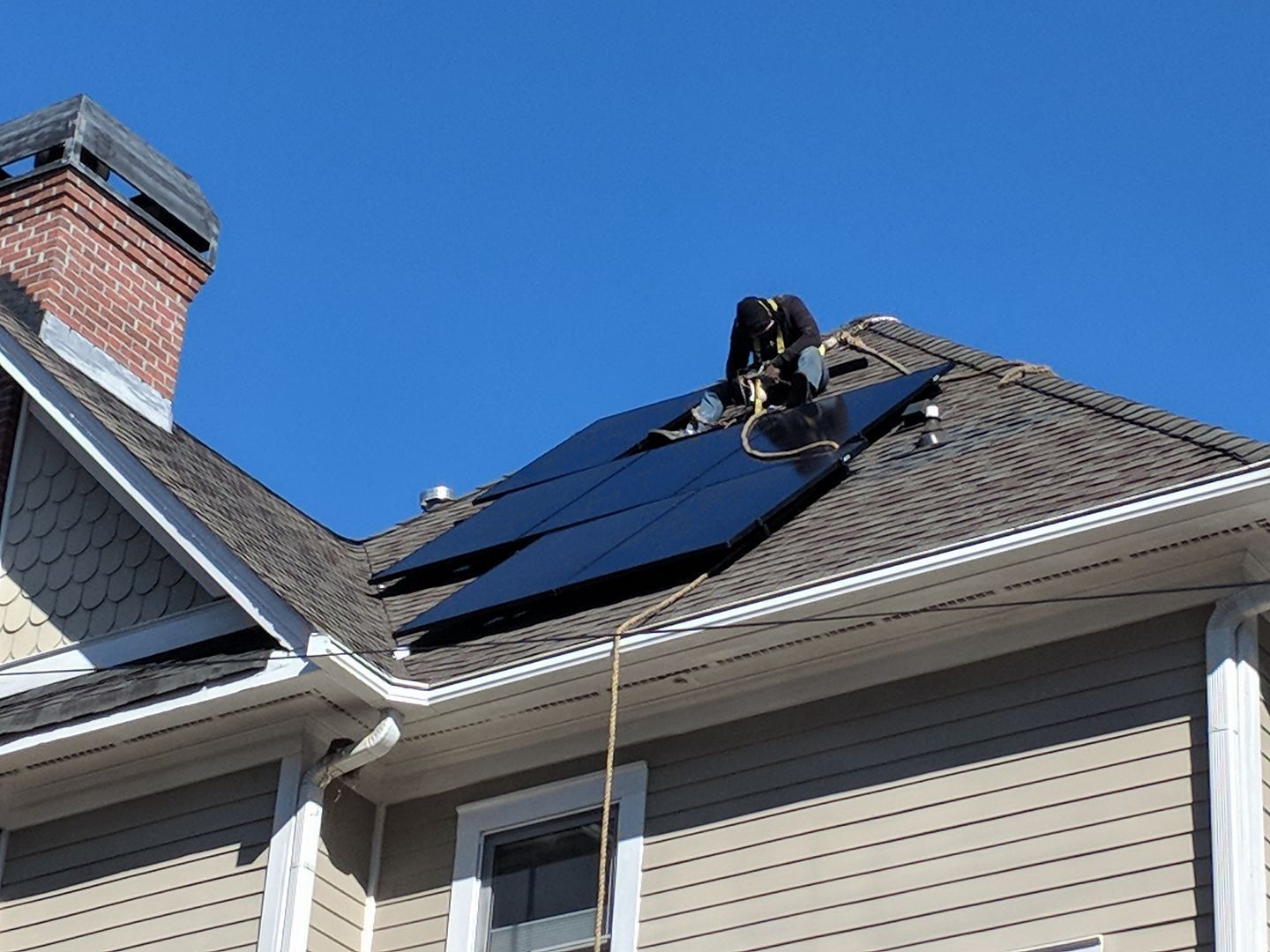 A person is installing solar panels on the roof of a house.