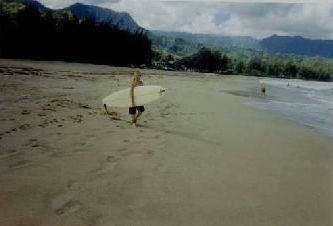 A person is carrying a surfboard on the beach.