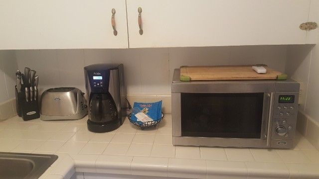 A kitchen counter with a microwave a coffee maker and a toaster