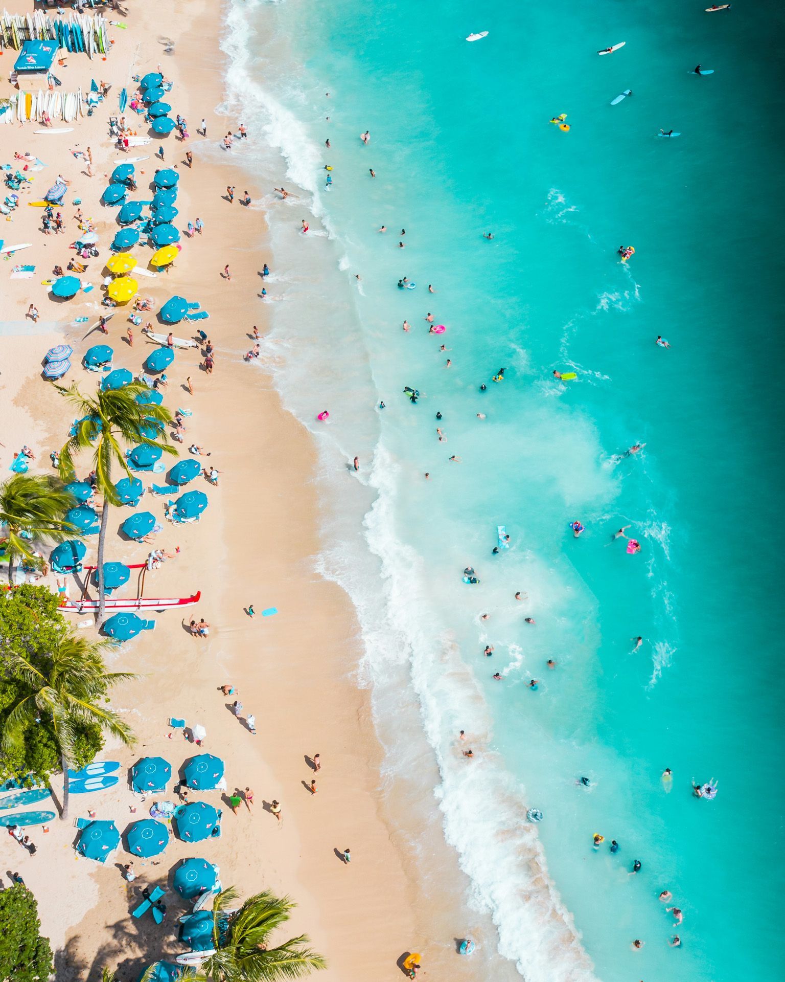 An aerial view of a beach filled with people and umbrellas.