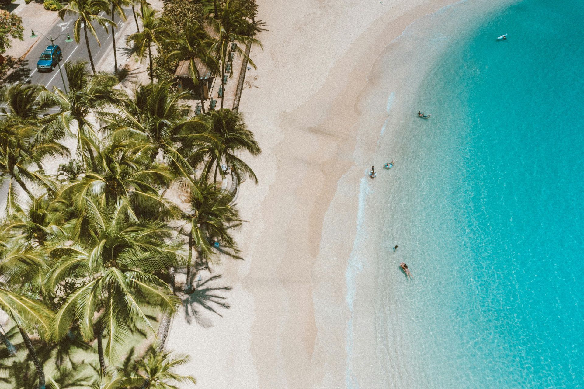 An aerial view of a tropical beach with palm trees and turquoise water.