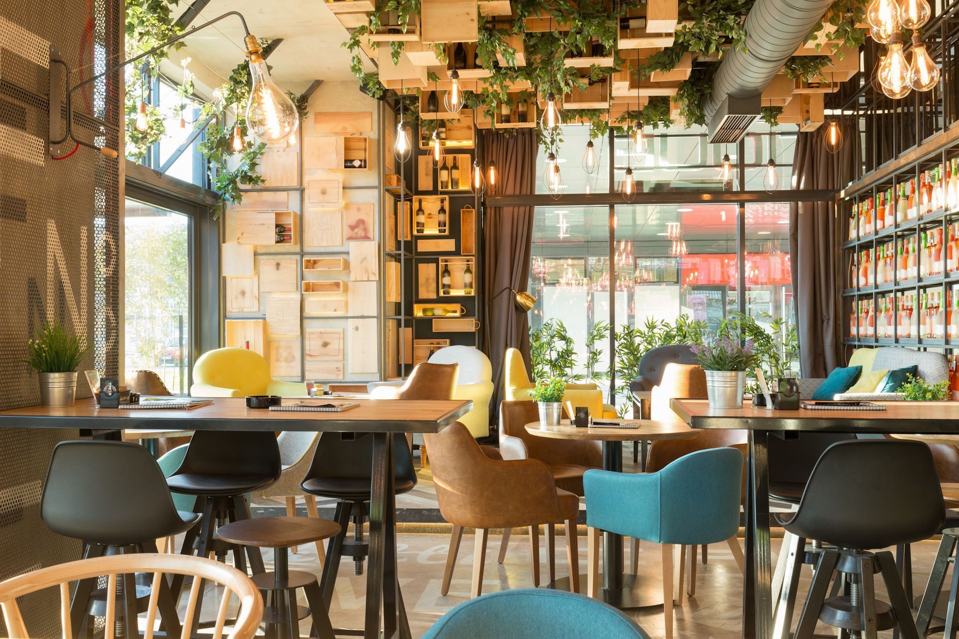 A restaurant with tables and chairs and plants hanging from the ceiling.