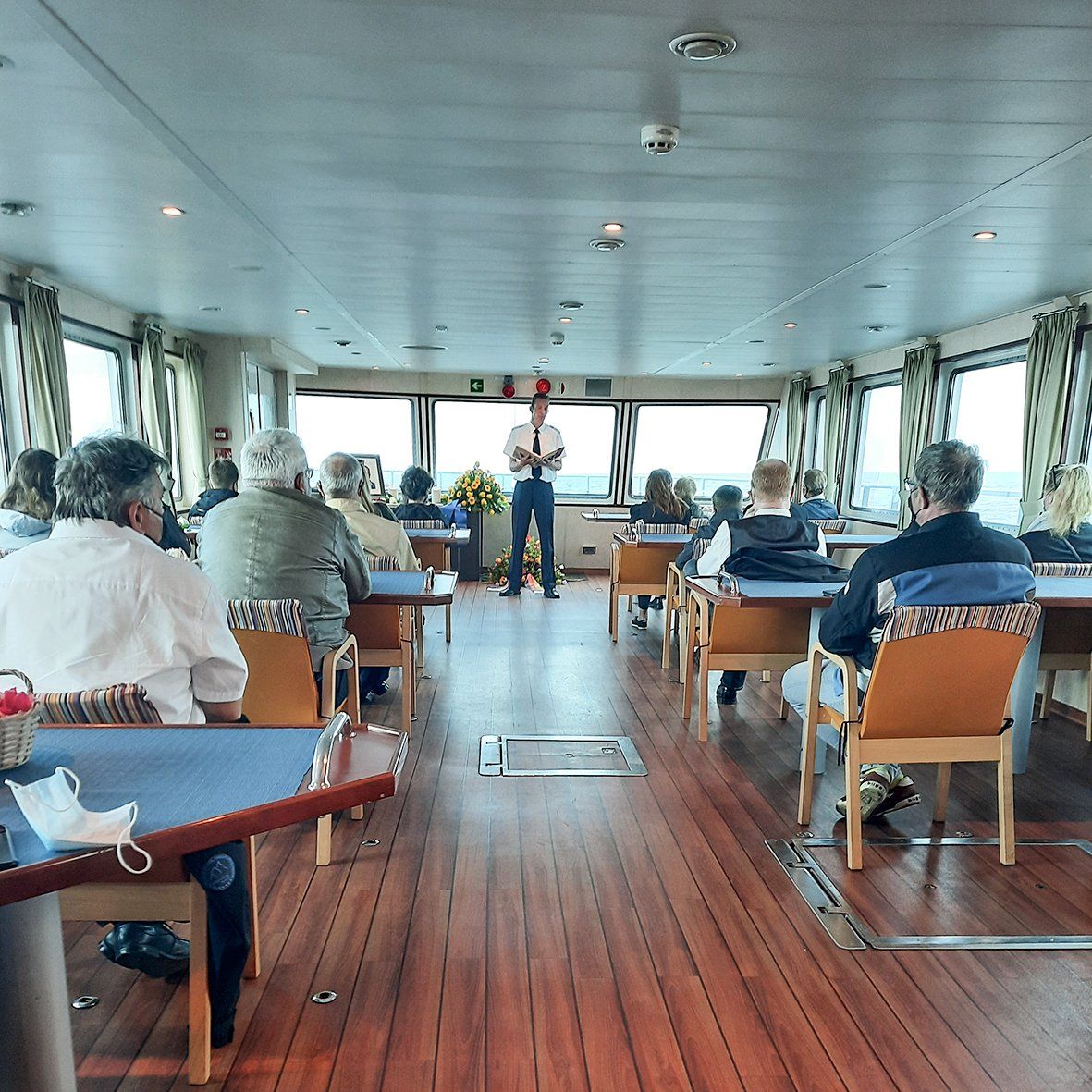 Ein Mann steht vor einer Gruppe von Menschen, die an Tischen sitzen