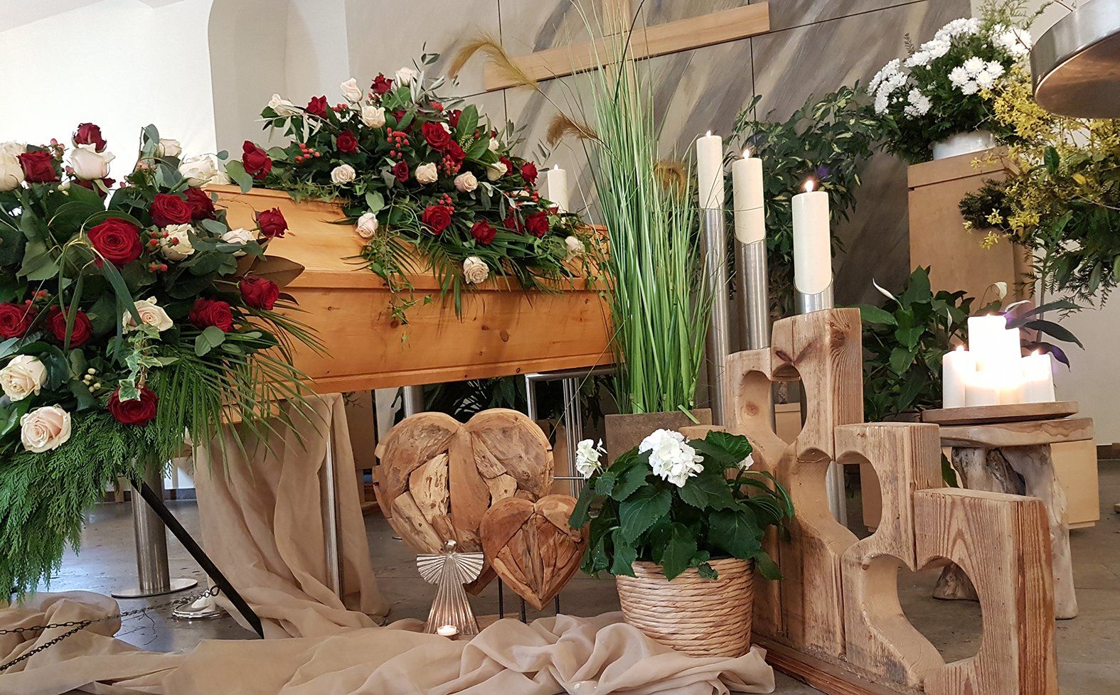 Ein Holzsarg ist von Blumen und Kerzen umgeben