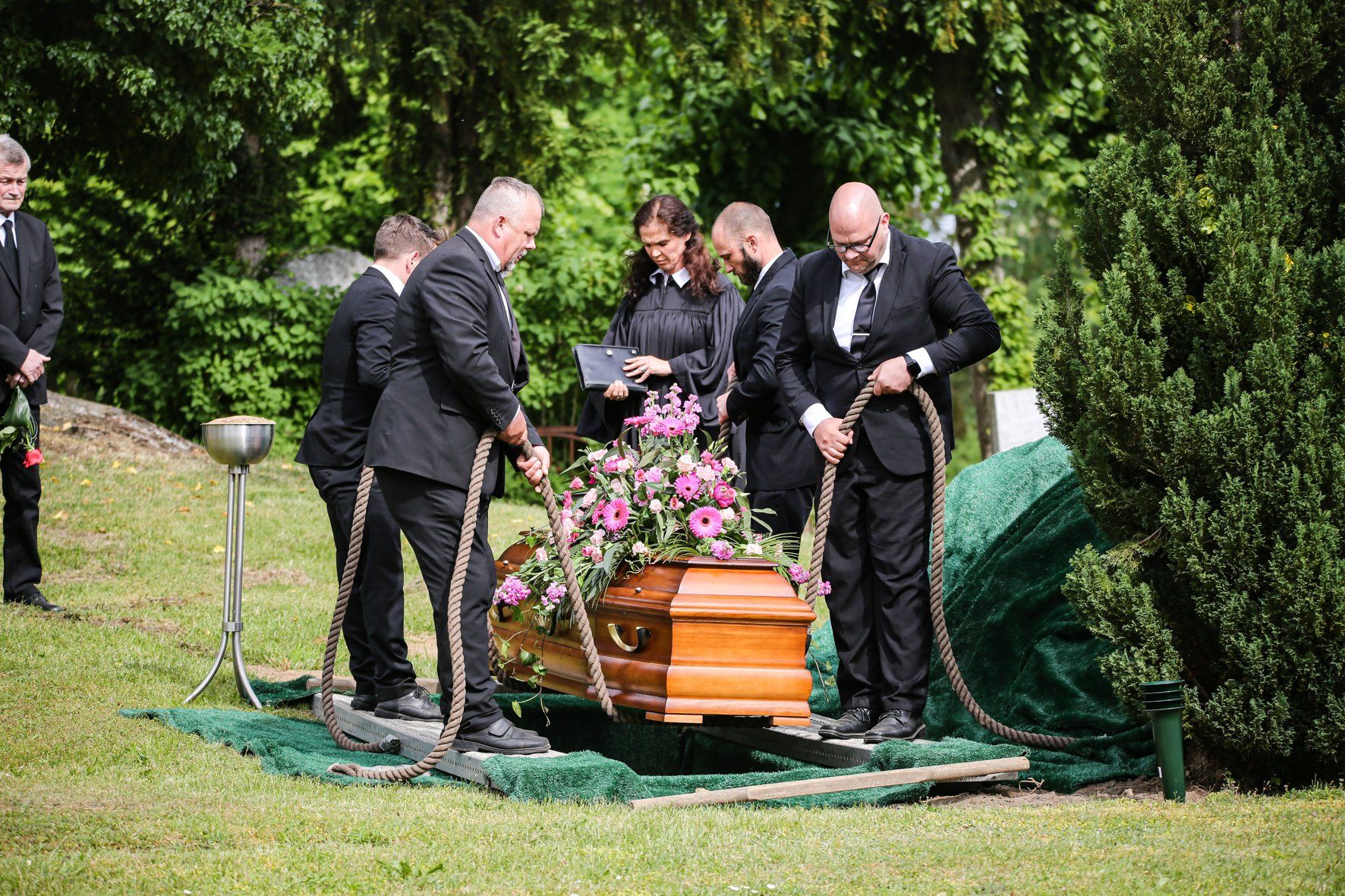 Eine Gruppe von Menschen trägt einen Sarg auf einem Feld