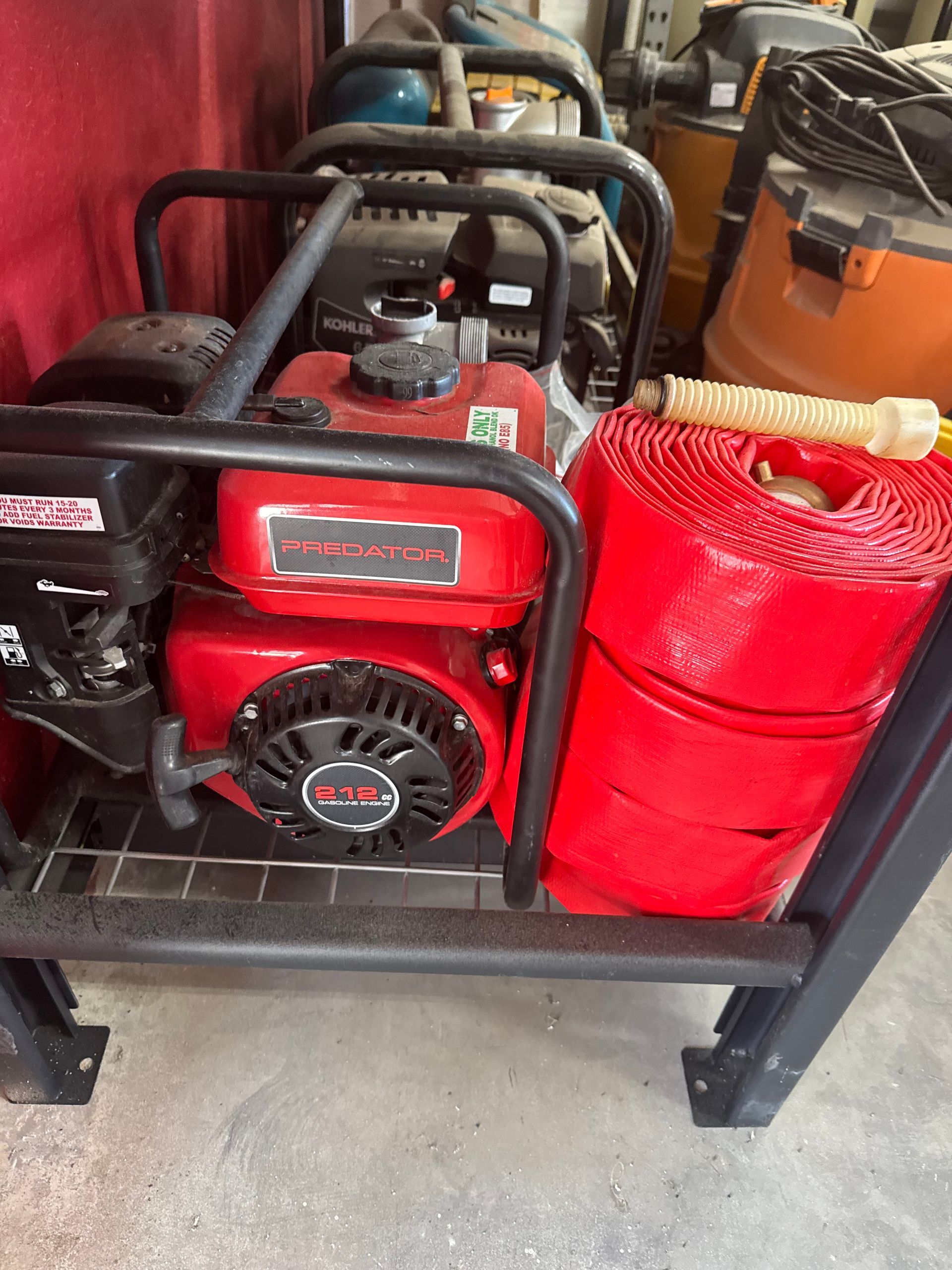Red gasoline engine with black metal cage and red hose.