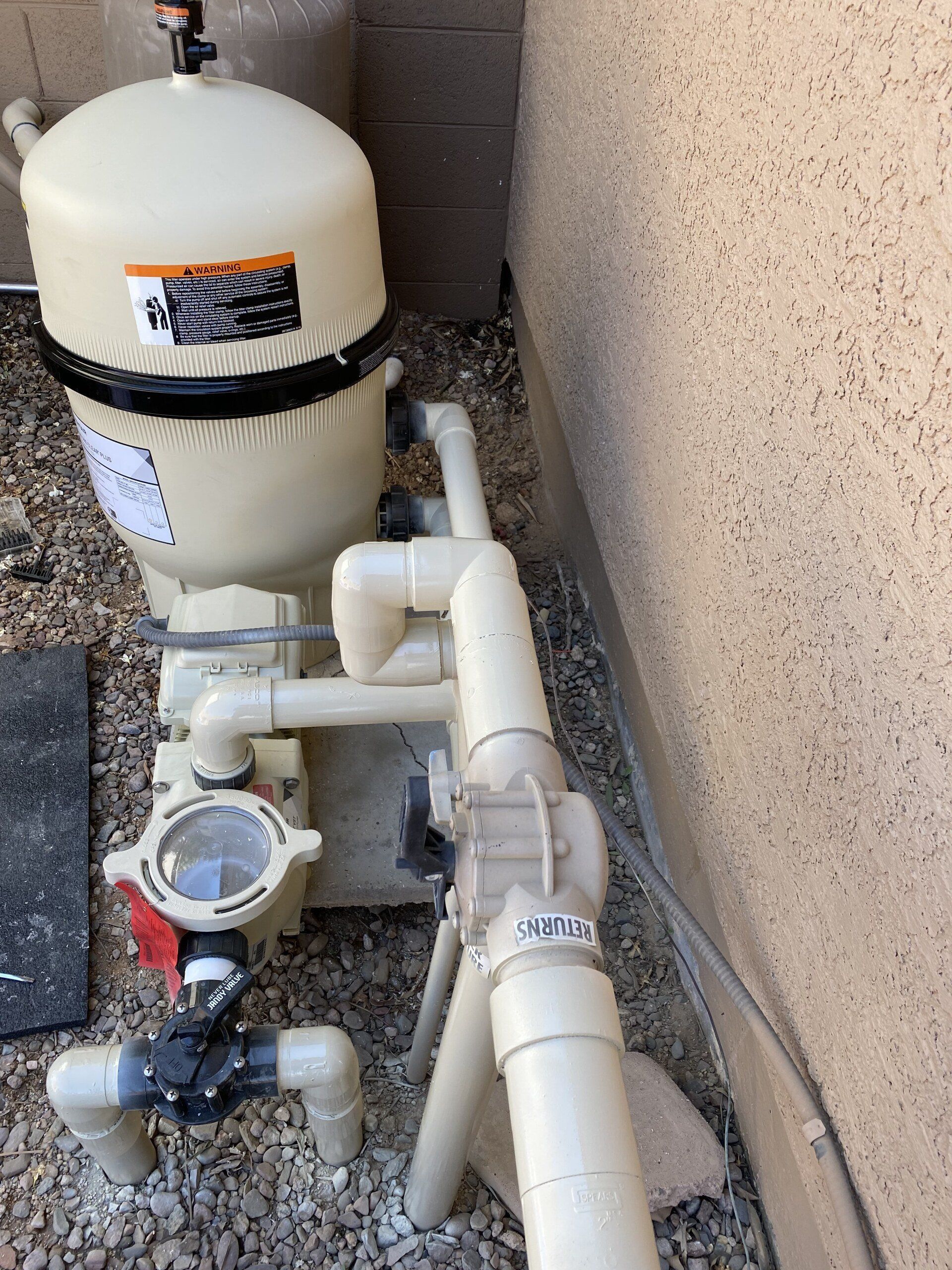 A swimming pool filter is sitting on the ground next to a wall.
