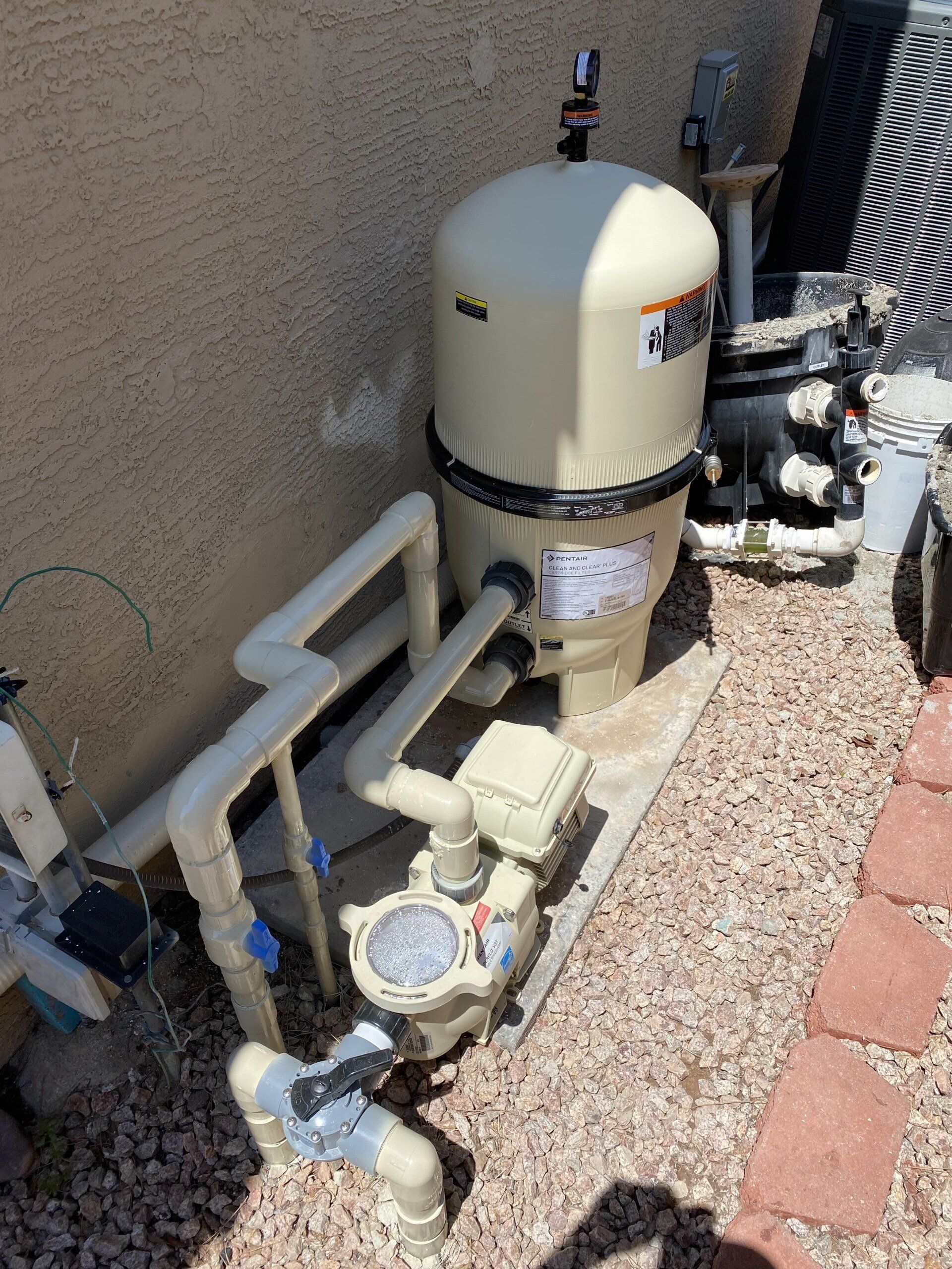A swimming pool filter is sitting on the ground next to a wall.