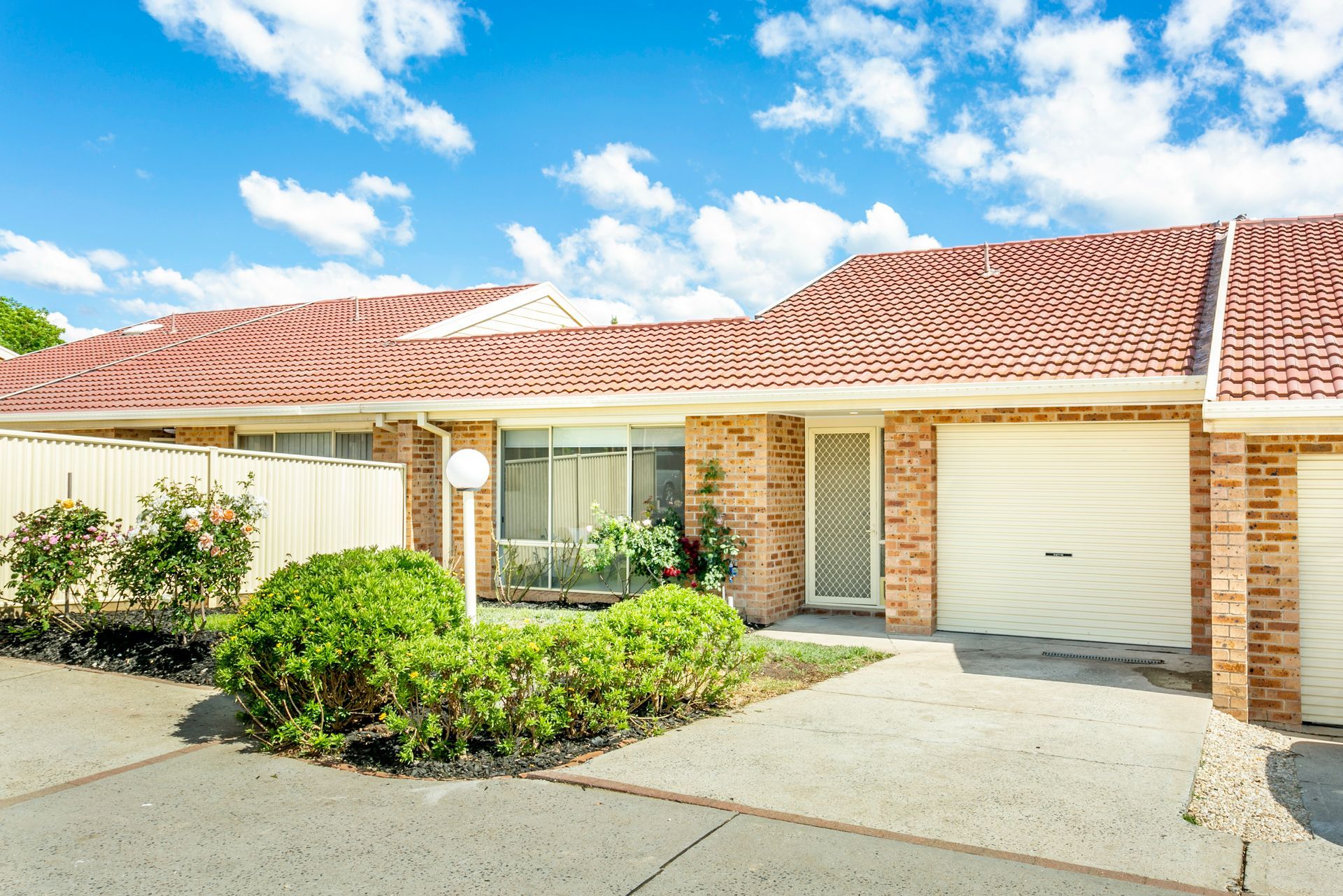 Bedroom with bed, bedside tables with lamps, window, and abstract blue artwork.