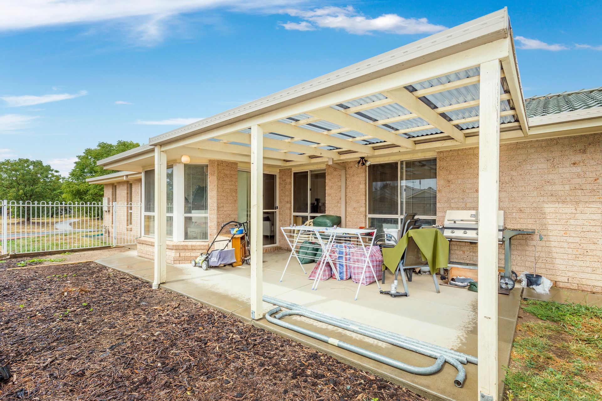 Covered patio with outdoor furniture, next to a brick home.