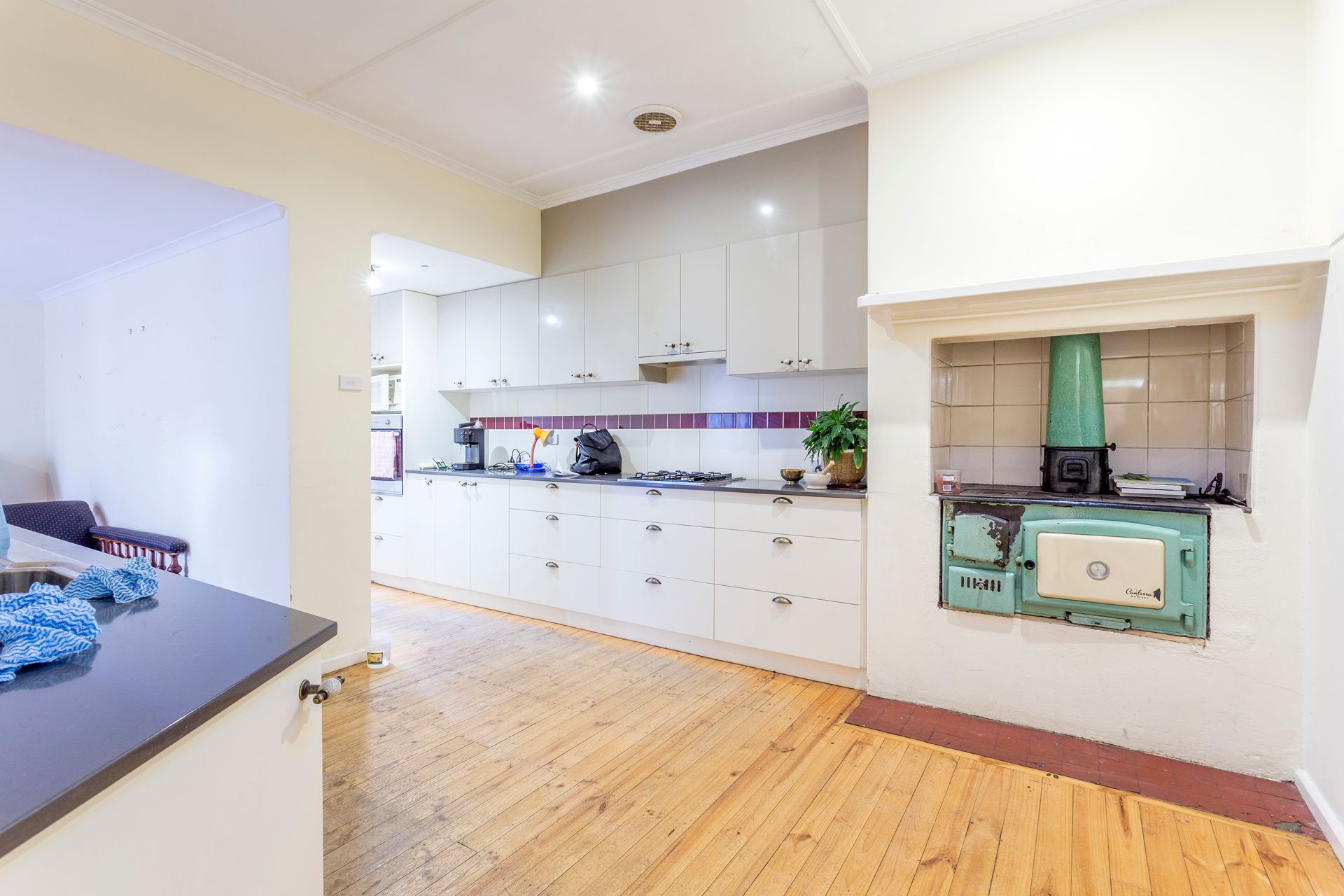 Kitchen with white cabinets, wooden floor, and antique green stove.