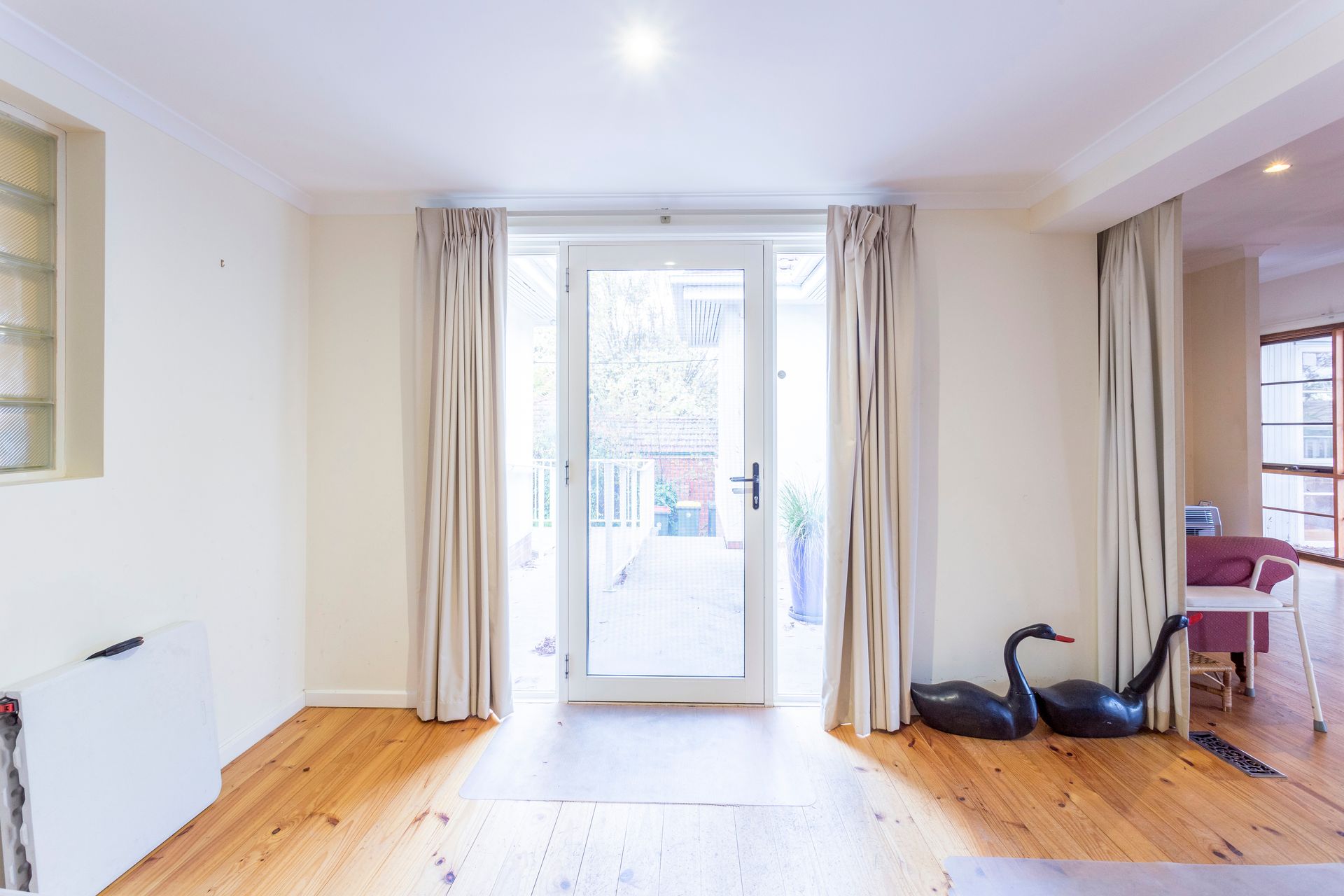 A small outdoor patio with a blue planter, sliding glass door, and a white handrail.