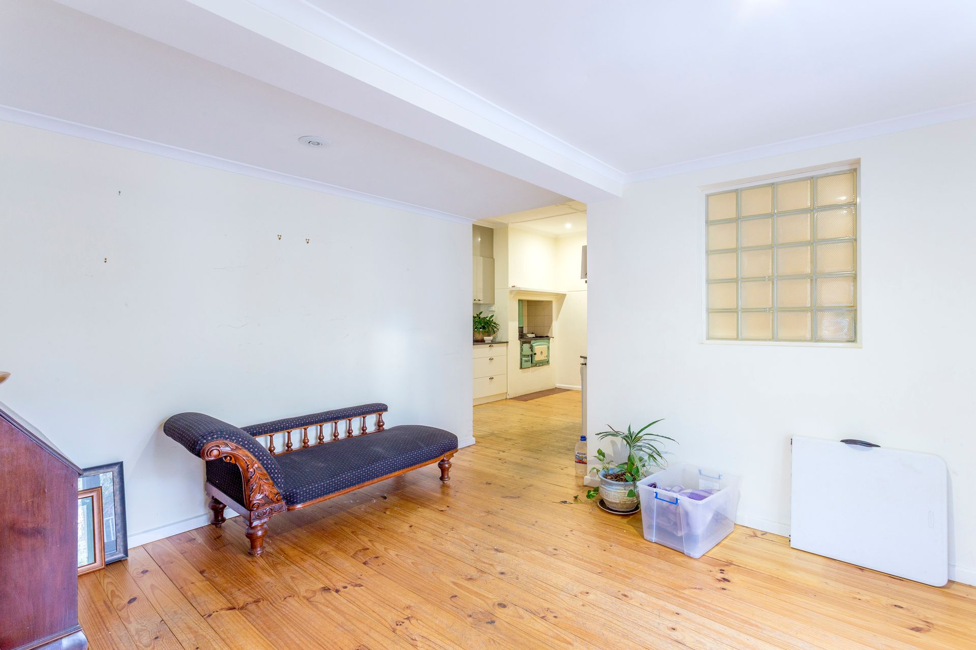 Walk-in closet with white shelves and drawers, a window, and wood flooring.