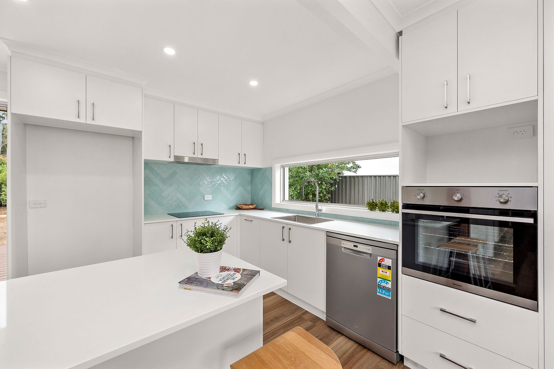 White laundry room with cabinets, counter, window, and shelves.