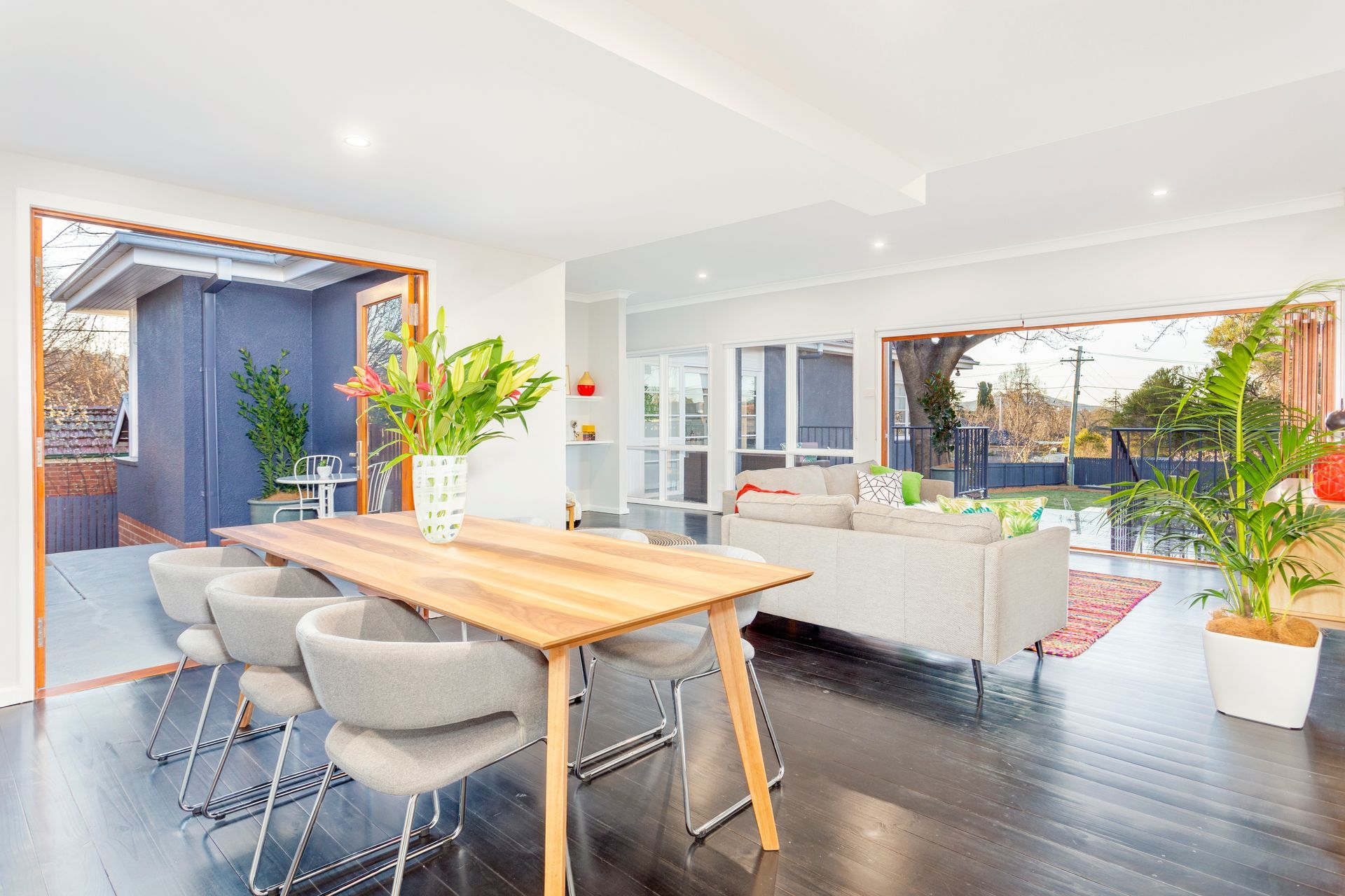 Bright, modern dining room with wooden table, gray chairs, and large windows.
