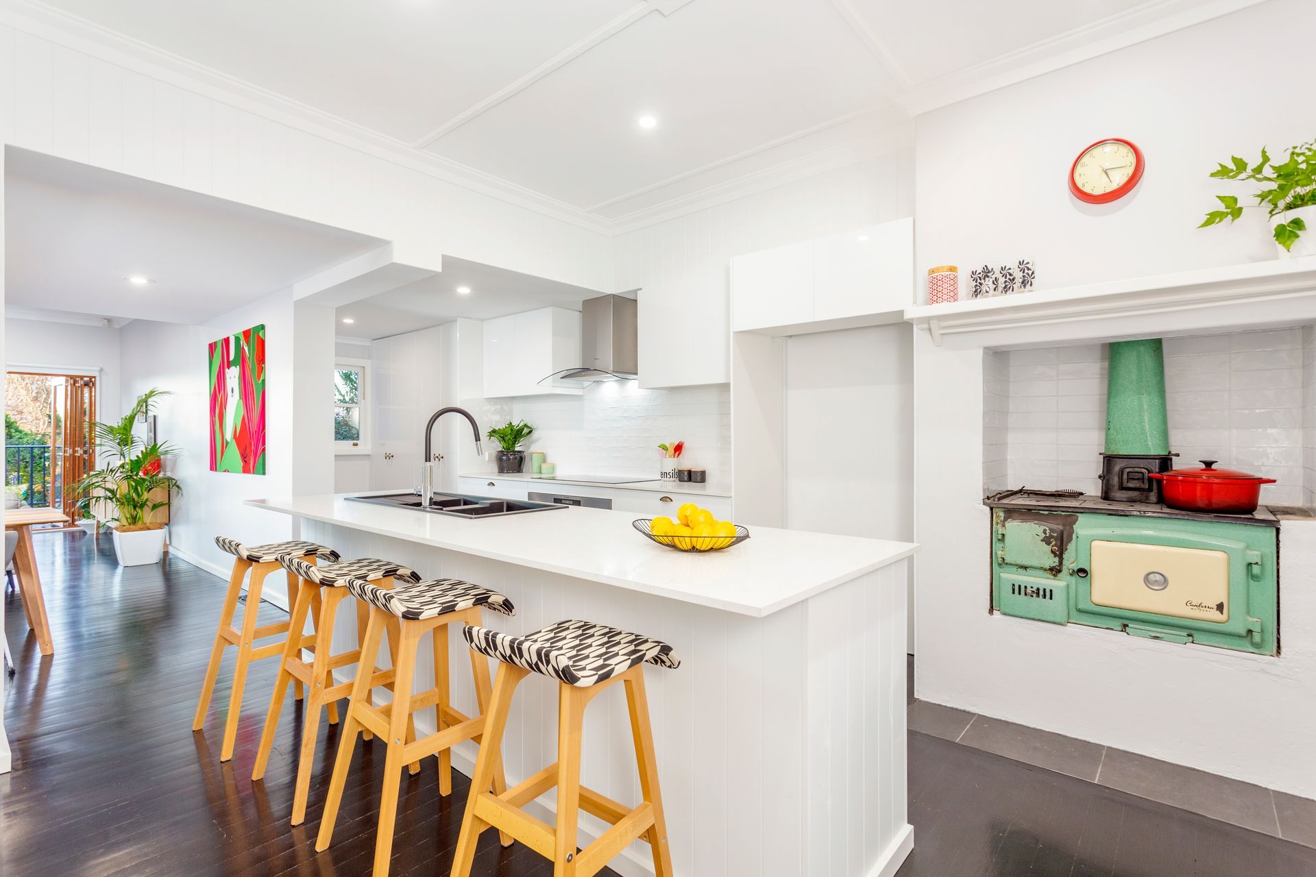 Bright kitchen with white counters, stools, and green vintage stove.